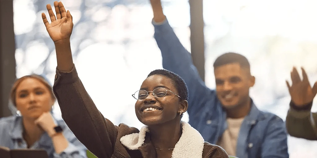 Nursing student eagerly raising hand in class.